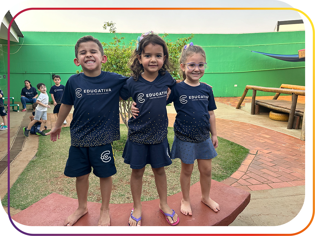 Alunos da educação infantil em cima do banco do pátio do colégio